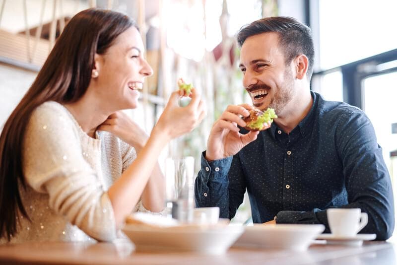 Beautiful young couple sitting in a cafe, having breakfast. Love, food, lifestyle